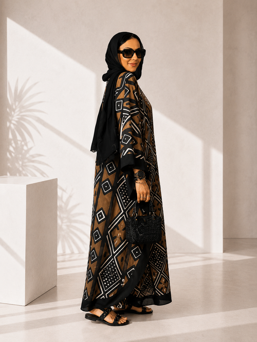 Woman wearing a long, patterned dress with a black hijab in a bright room.